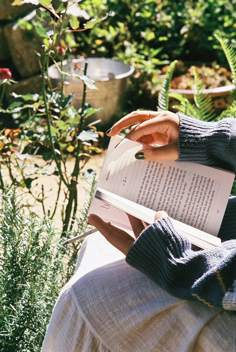 zoom nas maos de uma mulher lendo livro no jardim - Just Real Moms