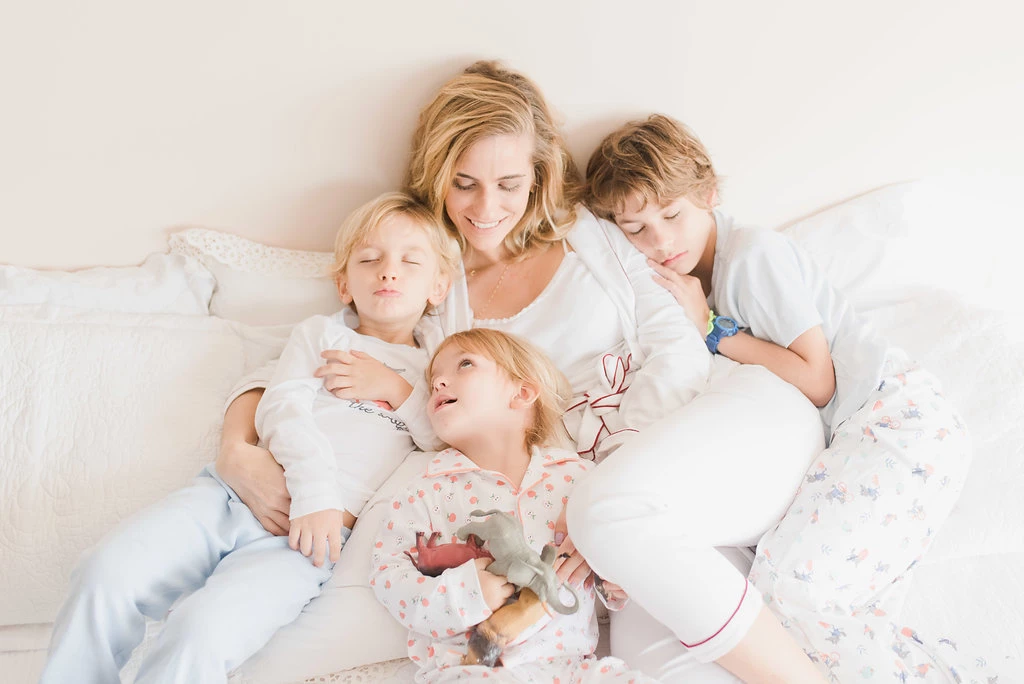 Leticia com os três filhos deitados na cama - Just Real Moms